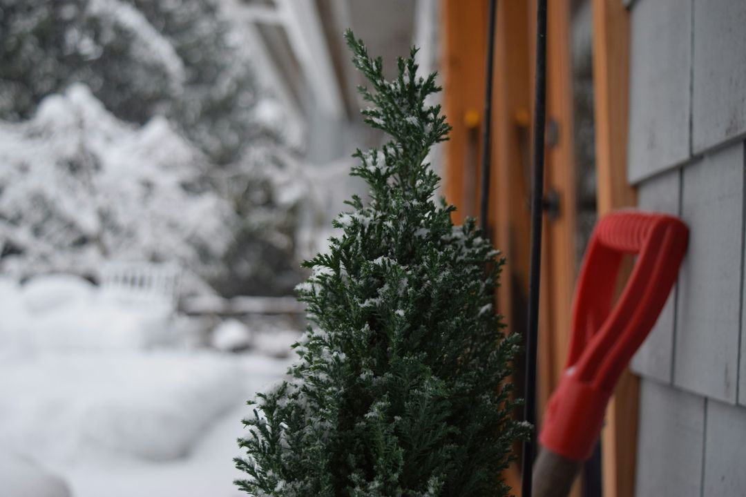 Rote Schneeschaufel im Schnee neben einem Haus